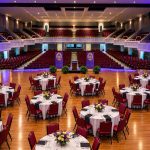 Elegant dining tables are on stage in Twichell auditorium with soft lighting.
