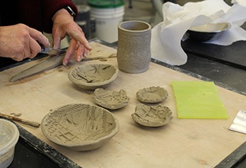 An attendee works with clay