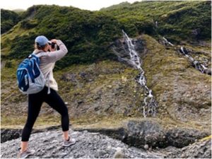 A student photographs a waterfall in New Zealand