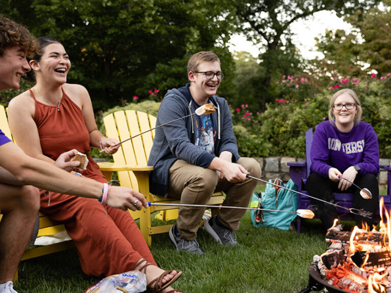 Students roast marshmallows around a fire pit in the fall.