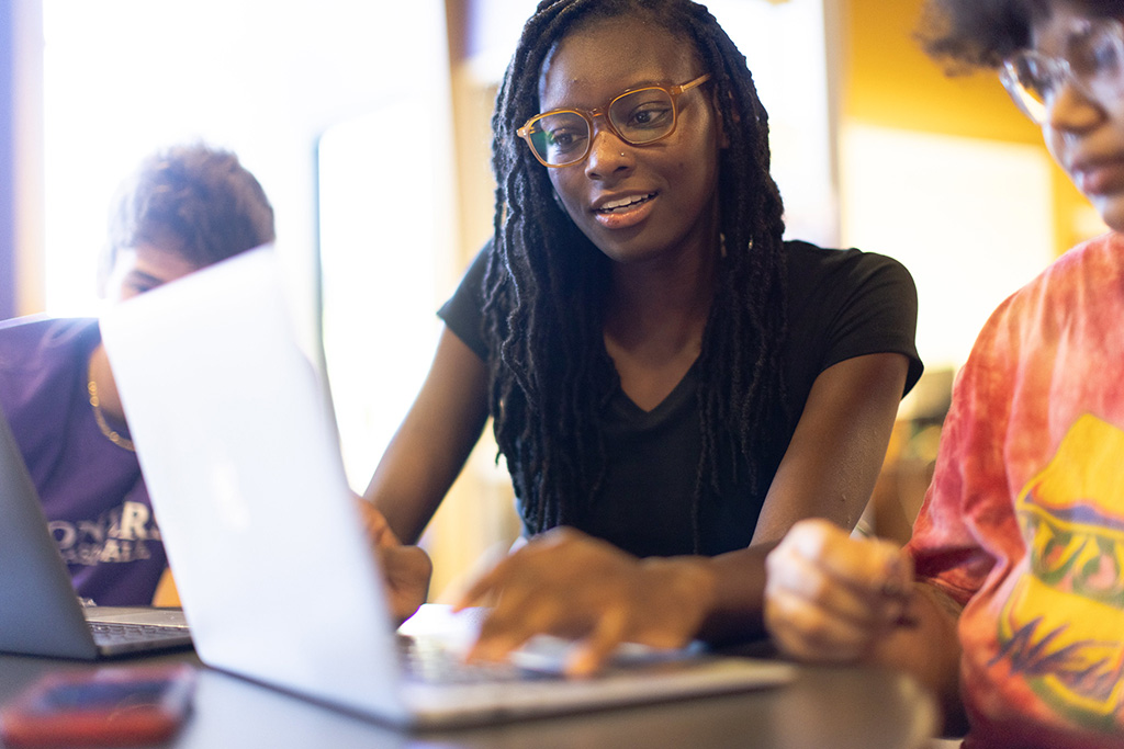 Two students work on a laptop.