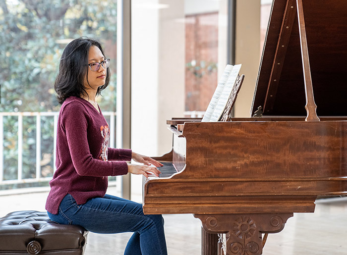 A Converse student plays a piece of music they composed at a piano.