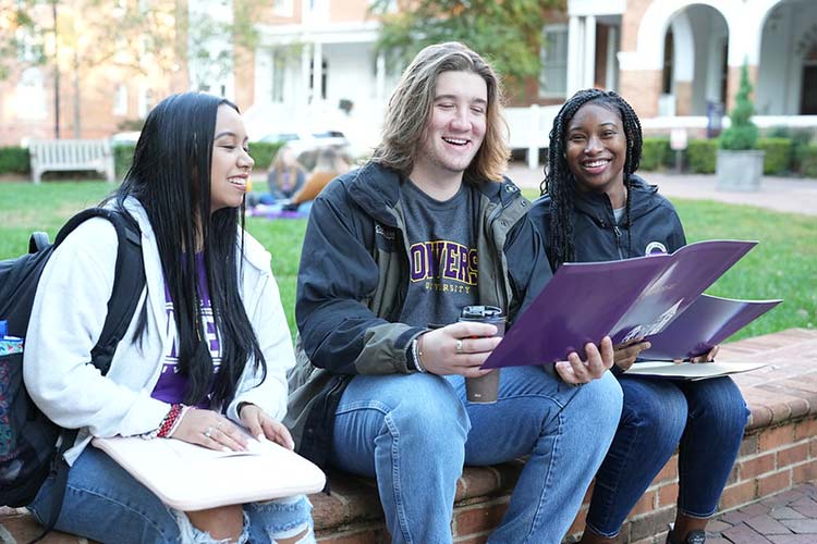Converse students look at required course materials while sitting outside Wilson Hall.