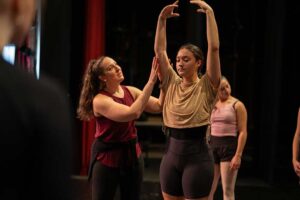 Converse faculty member helps a student adjust a dance position