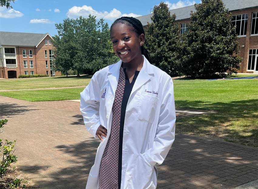 Eseose poses in a lab coat on the Converse campus