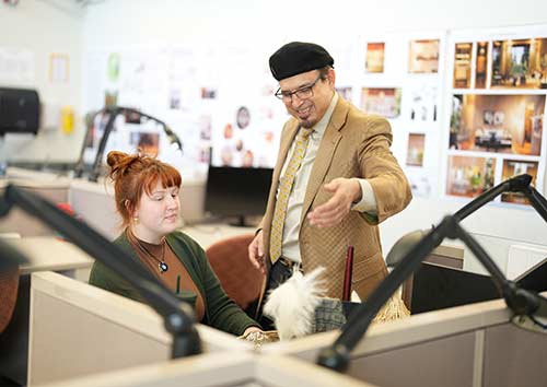 A faculty member shows an interior design student a technique.