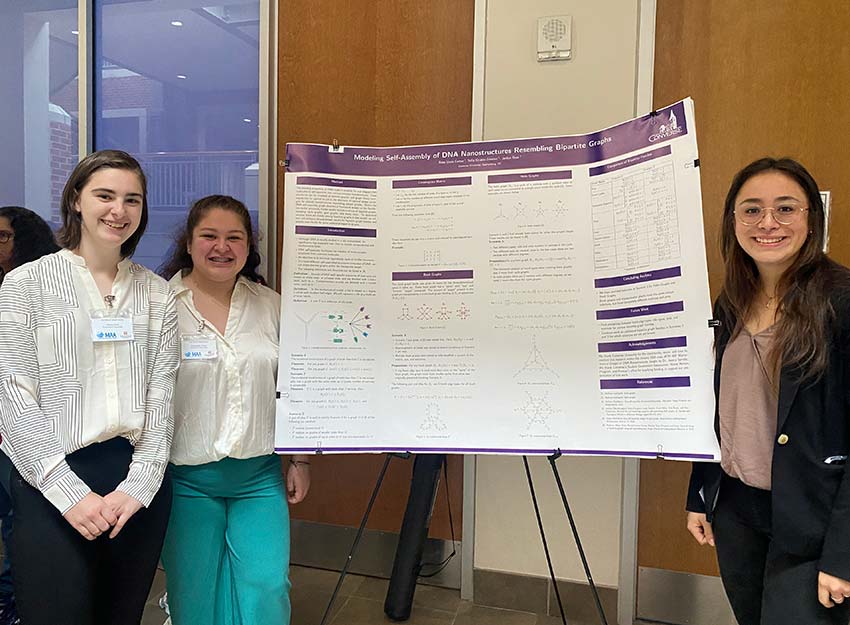 Three Converse math majors stand beside their research poster at the conference.