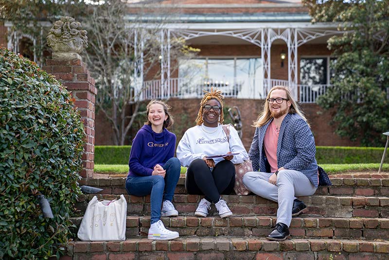 Three Converse students sit on campus.