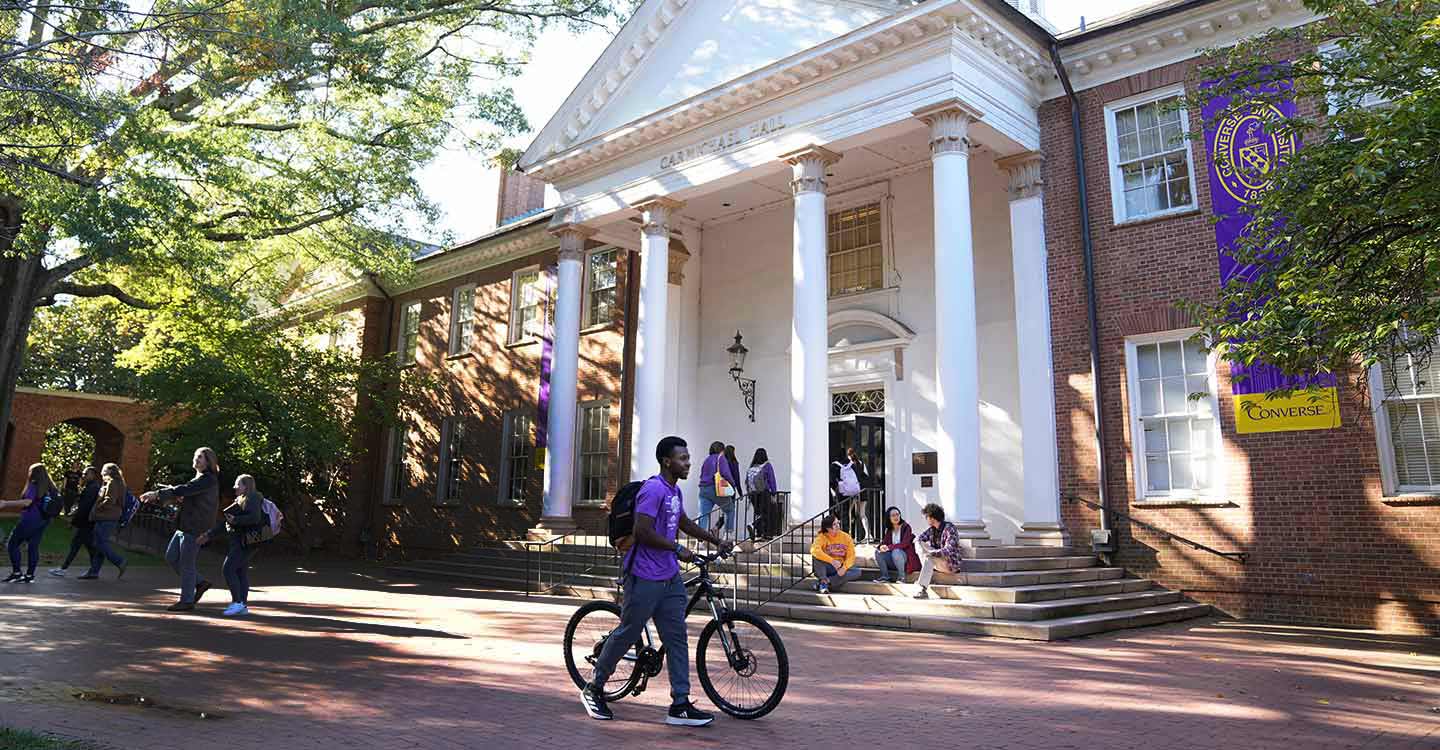 Converse students walk outside Carmichael Hall between classes on a sunny day