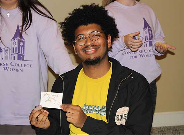 A Converse student at the CCW Period Party holds up a note of encouragement he wrote.