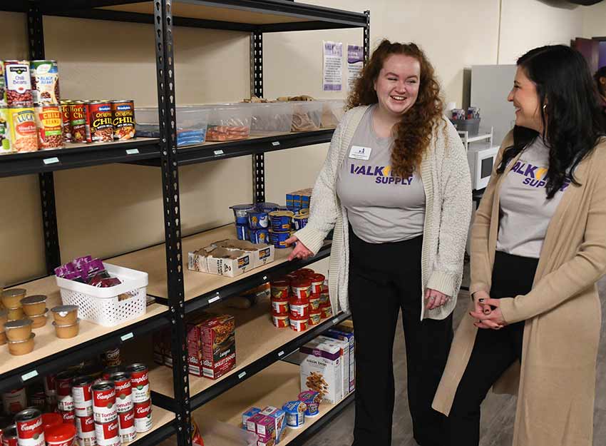 Converse's Chaplain stands with a student in Valkyrie Supply in front of shelves of food.