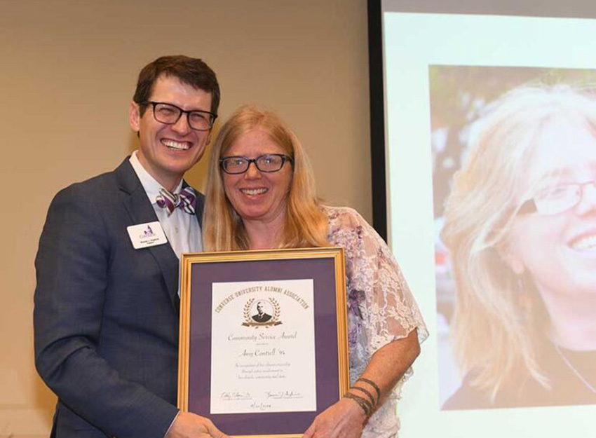 Amy Cantrell receives her alumni achievement award from Converse from President Boone J Hopkins.