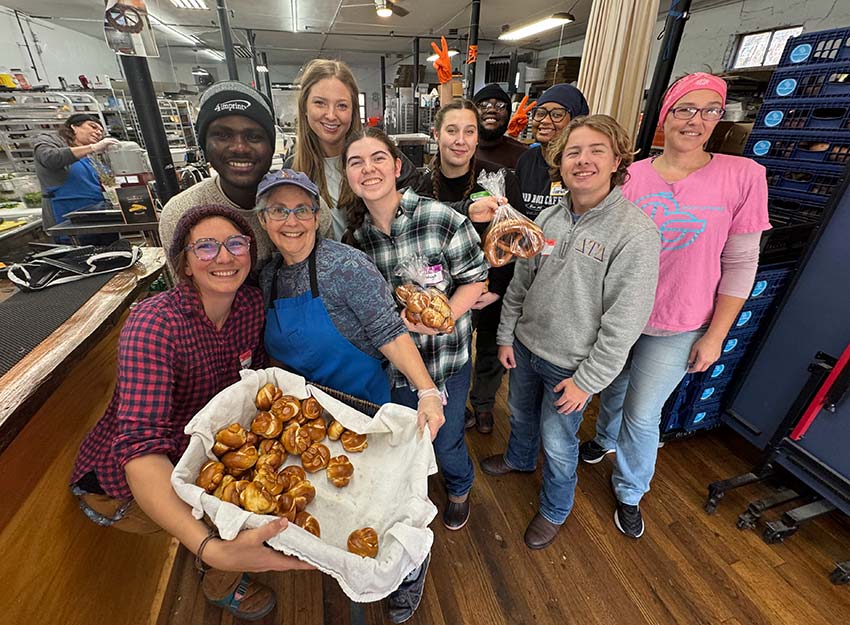 A group of volunteers hold up a basket of baked goods at Blunt Pretzels, an artisanal pretzel bakery in Swannanoa, NC
