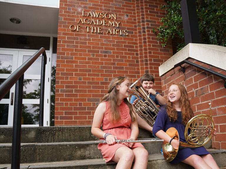 Image of young music students in front of the Lawson Academy of the Arts building.