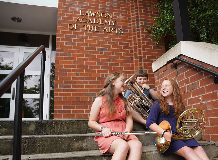 Image of young music students in front of the Lawson Academy of the Arts building.