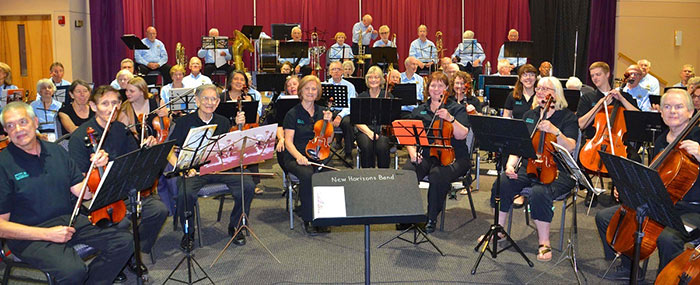 A group of adult music students on stage with their instruments.