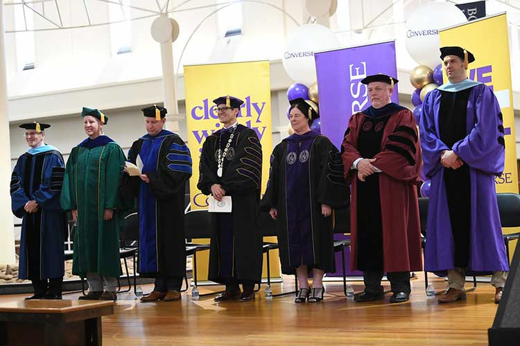 Converse faculty stand onstage at the 2025 UCG Hooding ceremony.