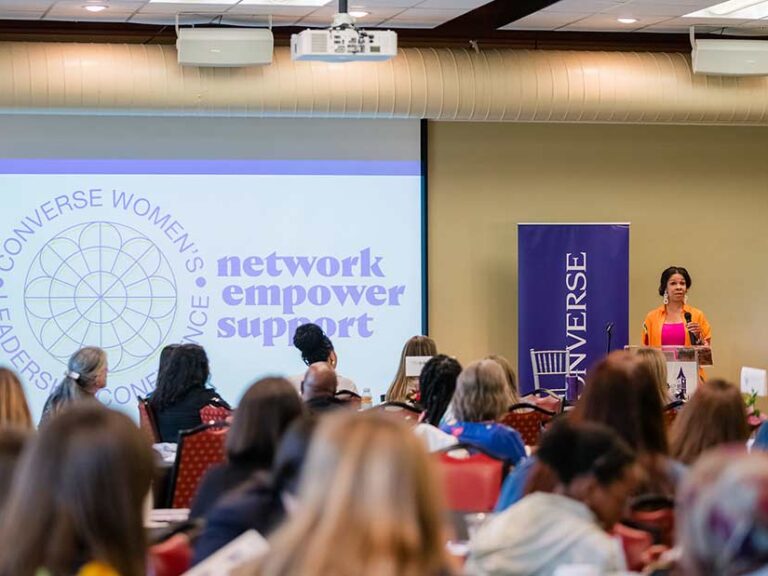 A speaker addresses a large audience at a previous Women's Leadership conference.