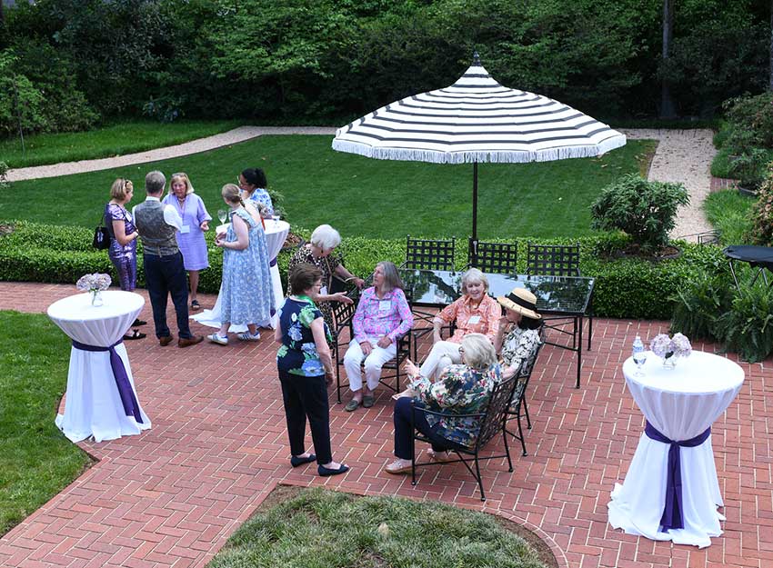 A group of donors mingle in the garden at the Converse Garden Party at the President's home.