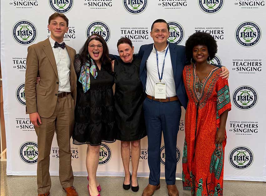 Brandi Icard stands with her students in front of a backdrop at the North American Teachers of Singing competition