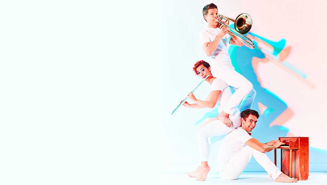 Three band members positioned on each others' backs while playing different instruments.