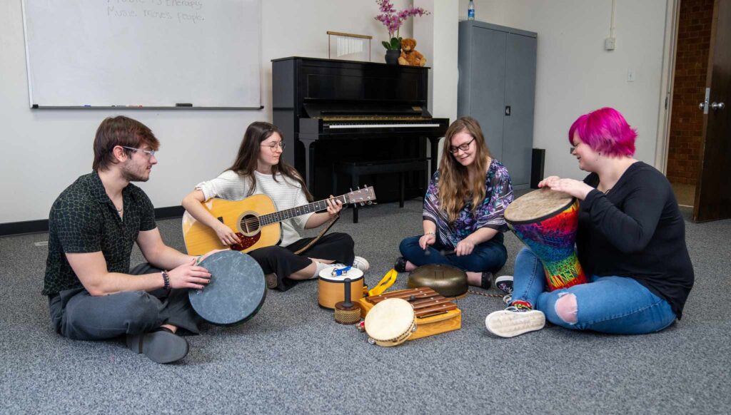 Four Converse music therapy students practice their instruments.