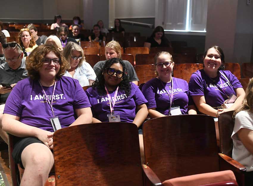 Four Converse students smile while wearing their first generation t-shirts that say, "I am first."