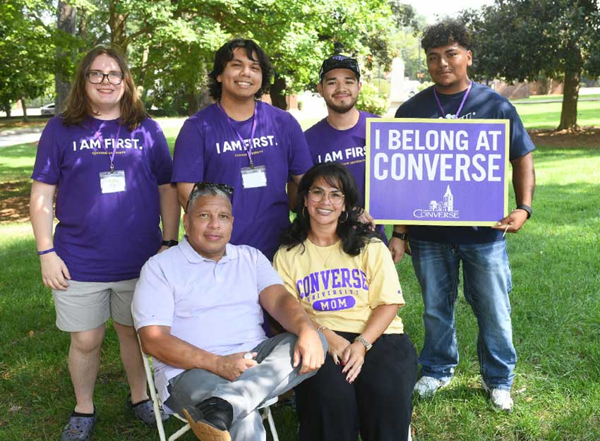A family smiles and pose with a sign that says, "I belong at Converse" during move in week at Converse University.
