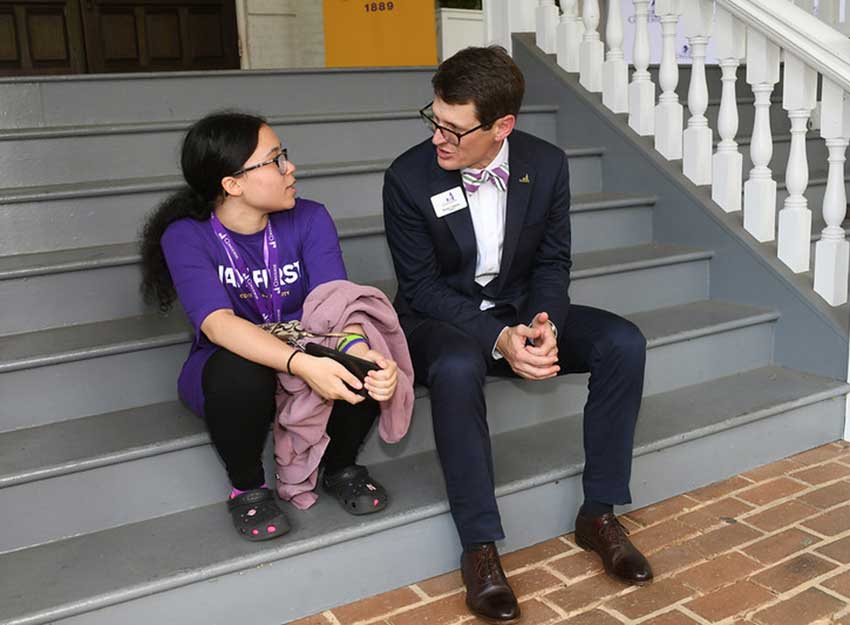 President Hopkins talks casually with a student moving in on the porch of Wilson Hall.