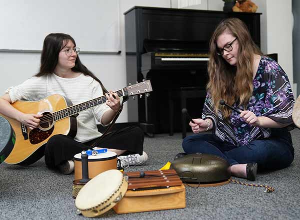 Two Converse Music Therapy students play instruments.
