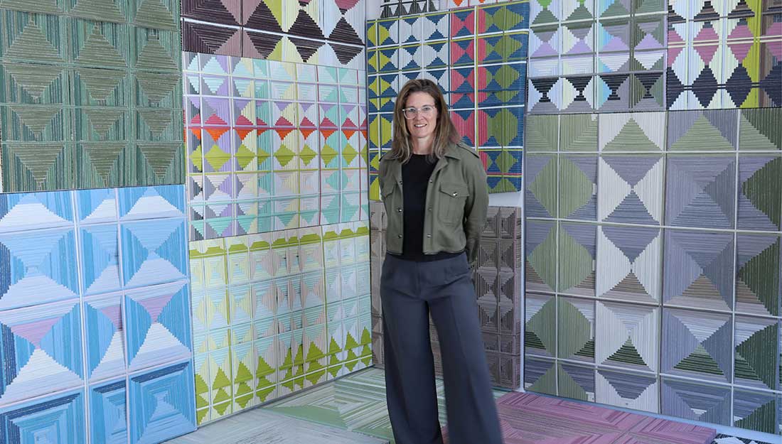 Artist Jean Alexander Frater stands in front of one of their paintings.