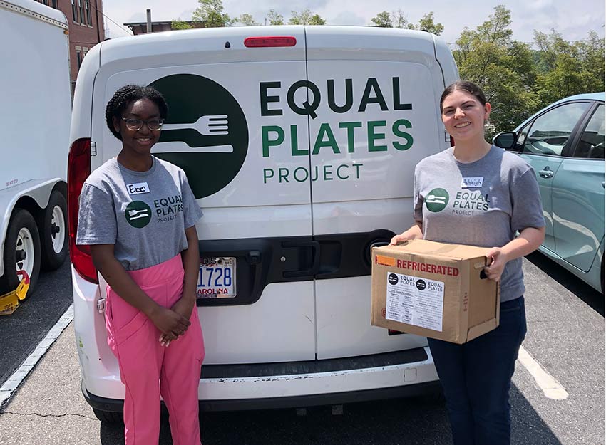 Ashleigh Austin stands with a friend beside an Equal Plates truck during her internship.