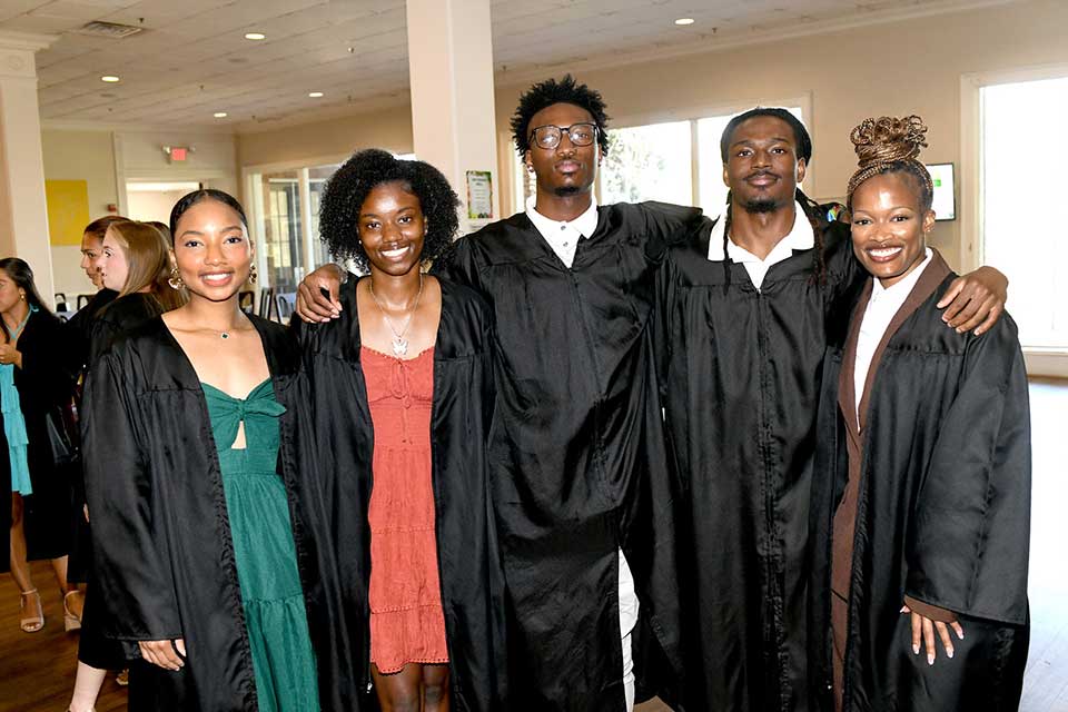 Five Converse students stand in Gee Dining Hall in their gowns before processing for Opening Convocation.