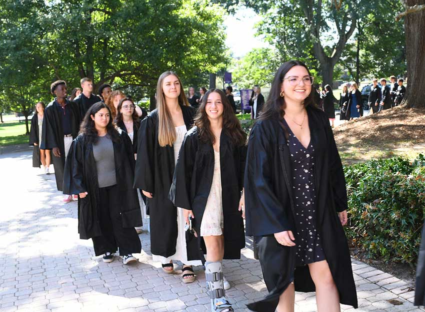 Students from the Class of 2026 process into Twichell Auditorium wearing their graduation gowns.