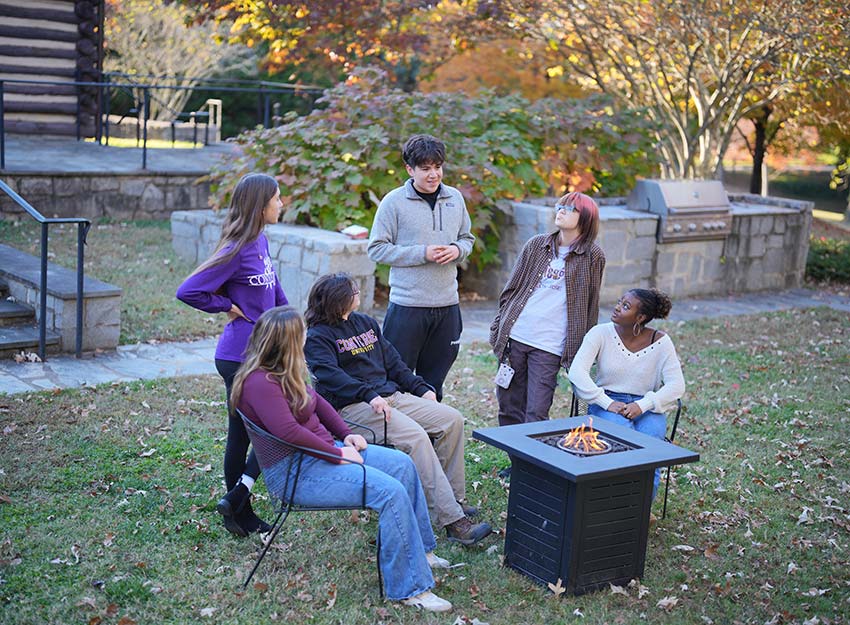 A group of Converse students gather around a fire pit on campus