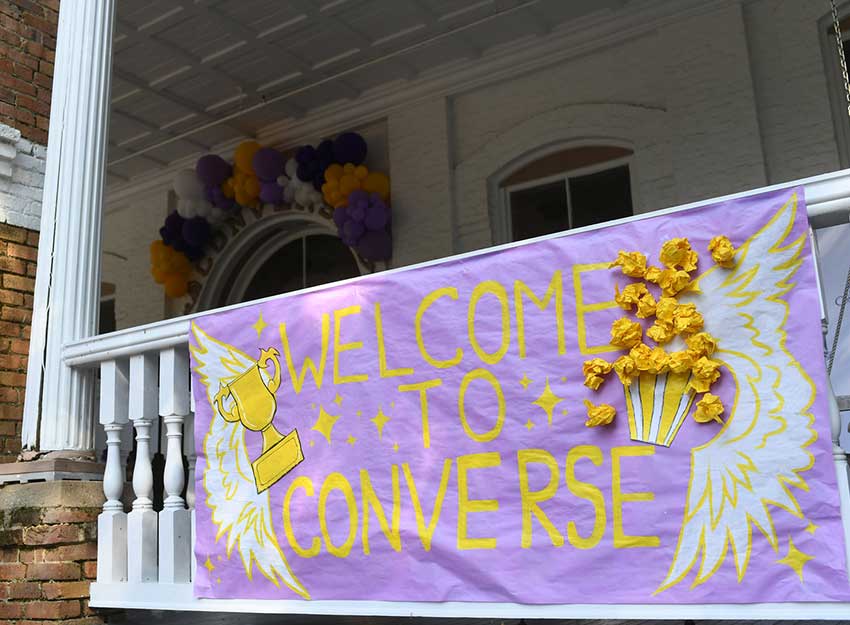 A large handmade sign hangs on campus that reads, "Welcome to Converse."