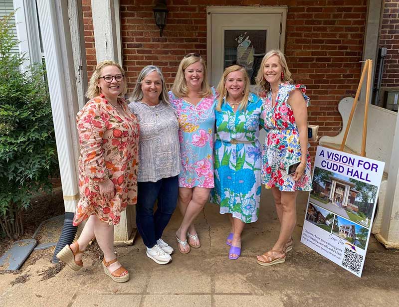 Converse alumni stand in front of a revitalized Cudd Hall.