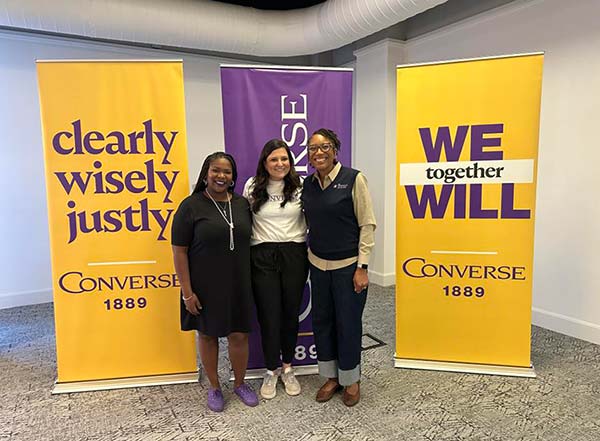 Converse volunteers stand in front of Converse University branded signs.