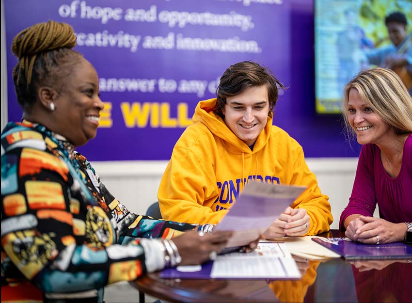 A student and their parent smile while talking with a Converse University financial aid representative.
