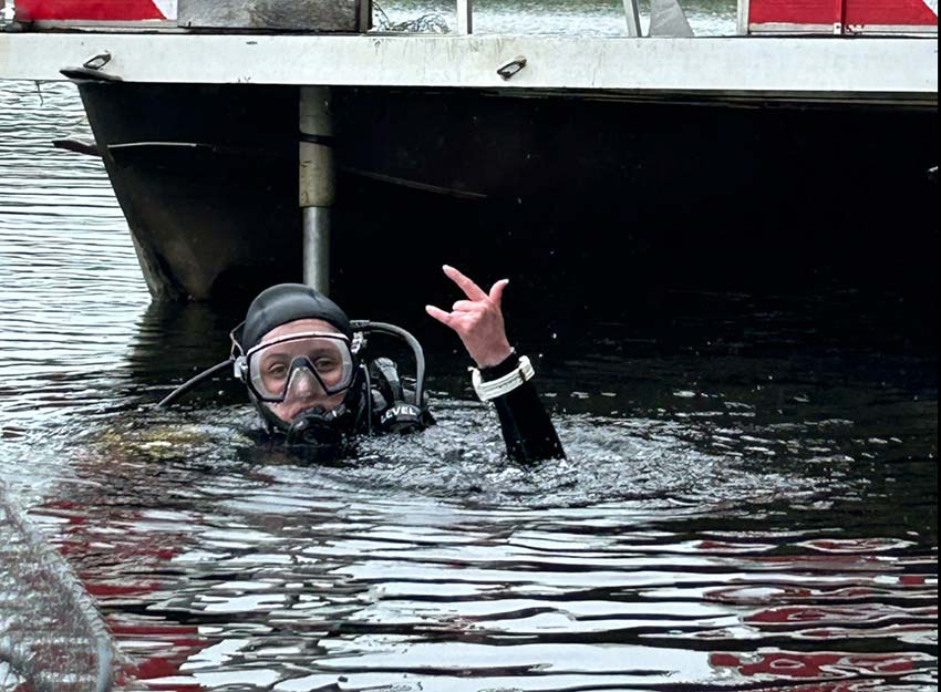 Wilson, wearing scuba gear, partially submerged in water.