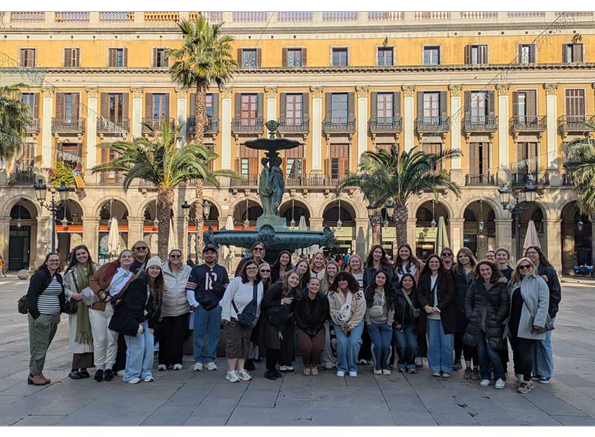 A group of Converse students and faculty stand in front of a popular landmark in Spain.