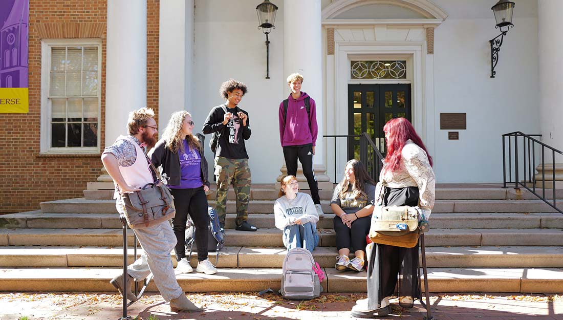 Students and faculty members mingle on the steps of a Converse campus building.