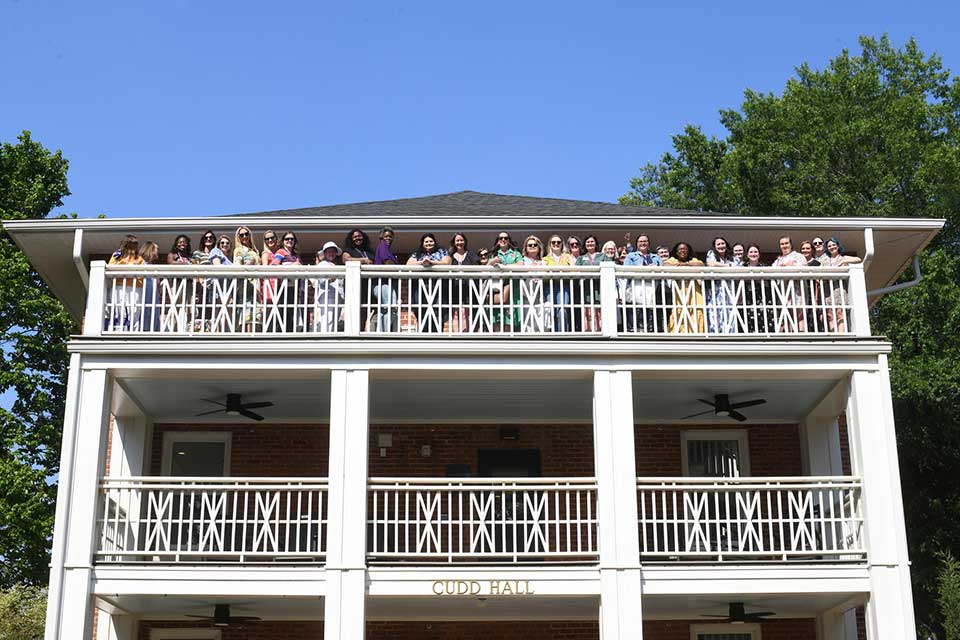 Converse alumni stand on the top floor of Cudd Hall balcony