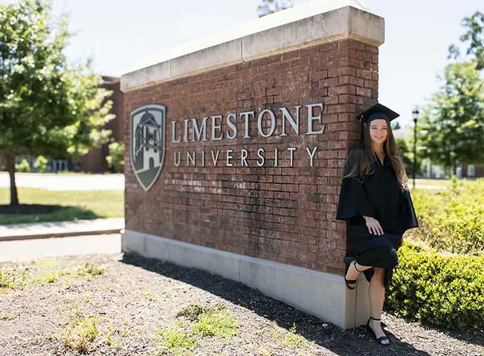 Rebekah stands in front of a Limestone University sign.