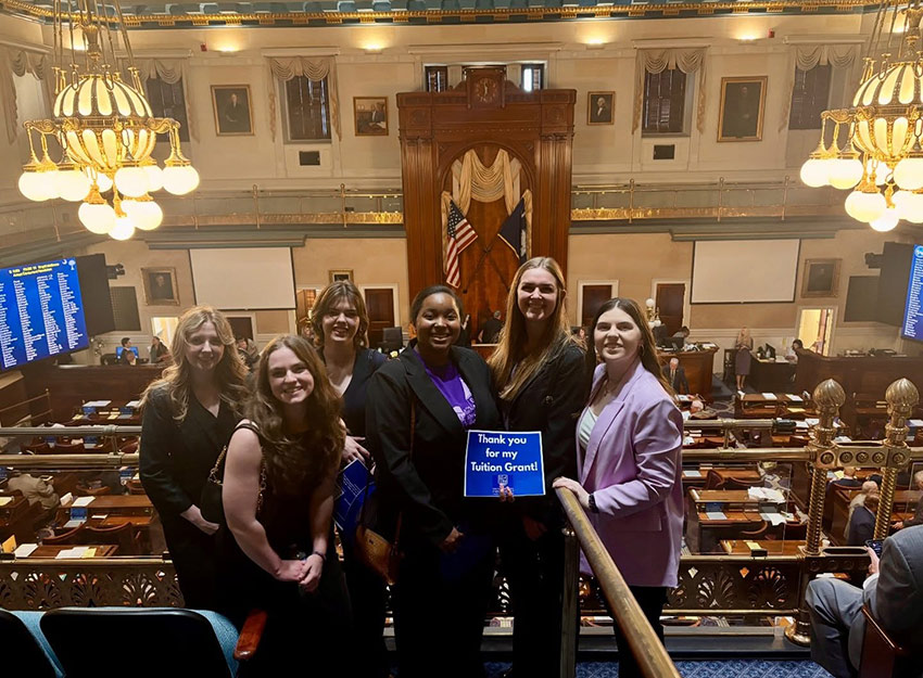 Converse students stand in the State House holding a sign that reads 'Thank you for my tuition grant"