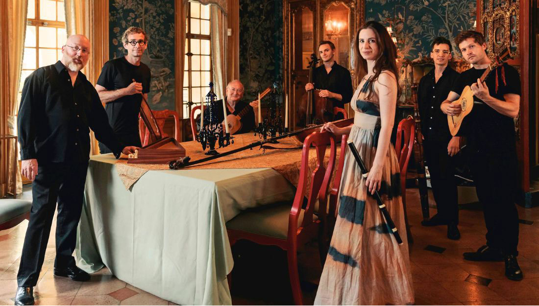 Members of Ruckus stand in an ornate room holding their instruments.