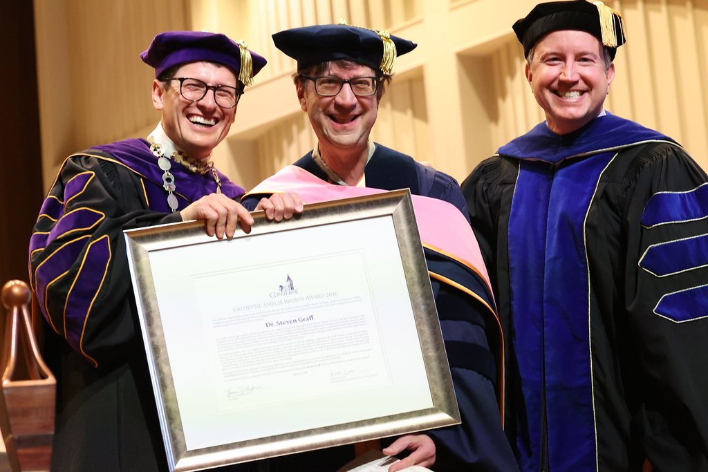 Dr. Graff stands on stage holding an award