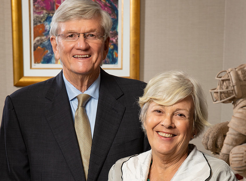 A portrait photo of Mike and Gillian Goodrich against a purple background